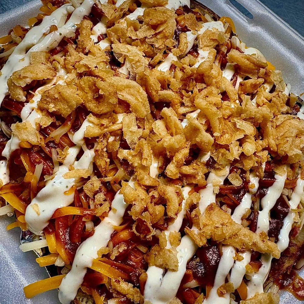 A BBQ brisket potato boxed to go, with ranch and crispy fried onions